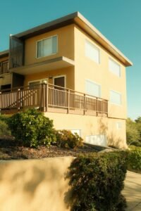 Photo by Dan Begel Modern yellow building with wooden balcony and glass details.